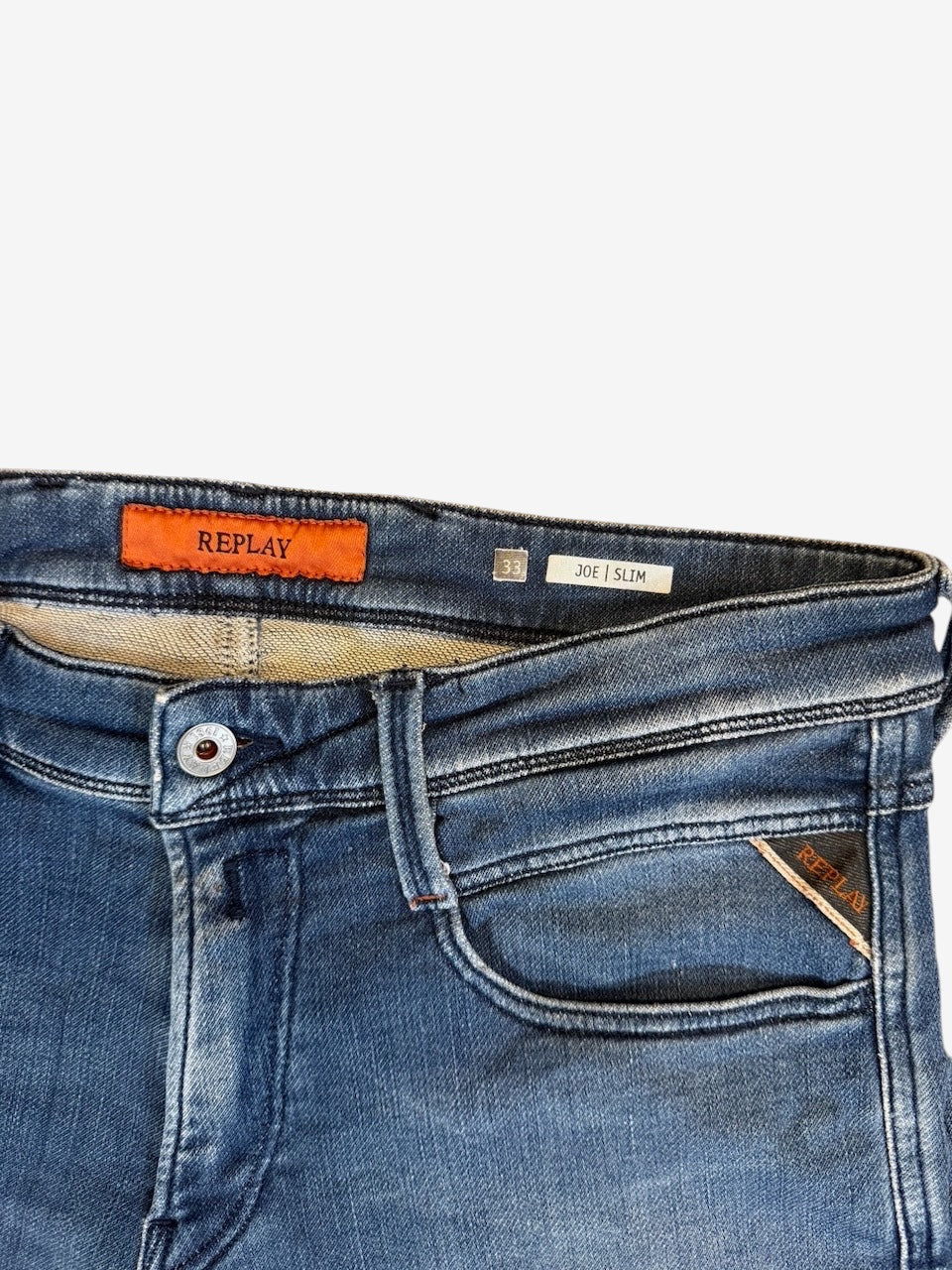 Nordic Jeans Co. REPLAY Joe slim fit denim jeans in a medium-blue wash with branded hardware and orange logo patch.
